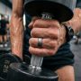 Matte black smart fitness ring on a wooden desk next to a smartphone.